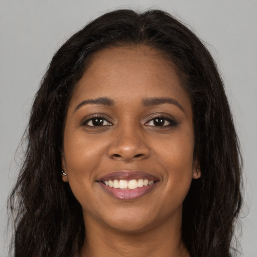 Joyful black young-adult female with long  brown hair and brown eyes