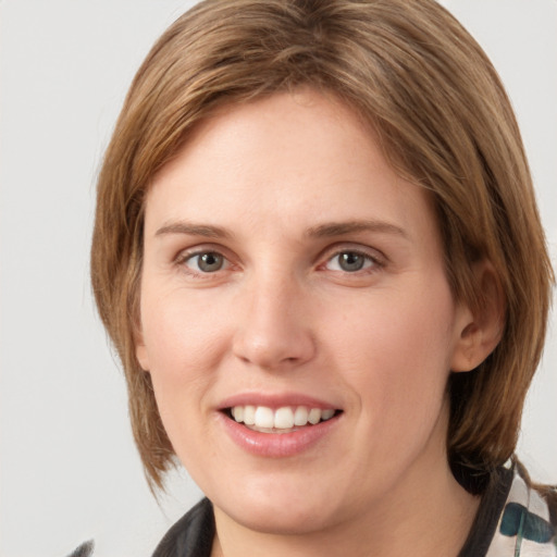 Joyful white young-adult female with medium  brown hair and grey eyes