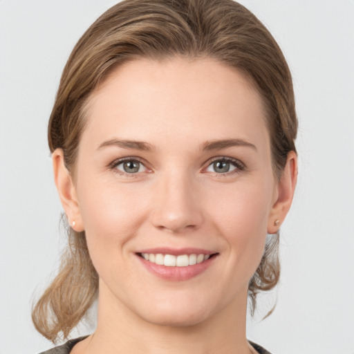 Joyful white young-adult female with medium  brown hair and grey eyes