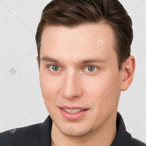 Joyful white young-adult male with short  brown hair and grey eyes