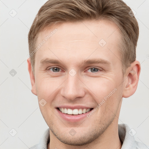 Joyful white young-adult male with short  brown hair and grey eyes