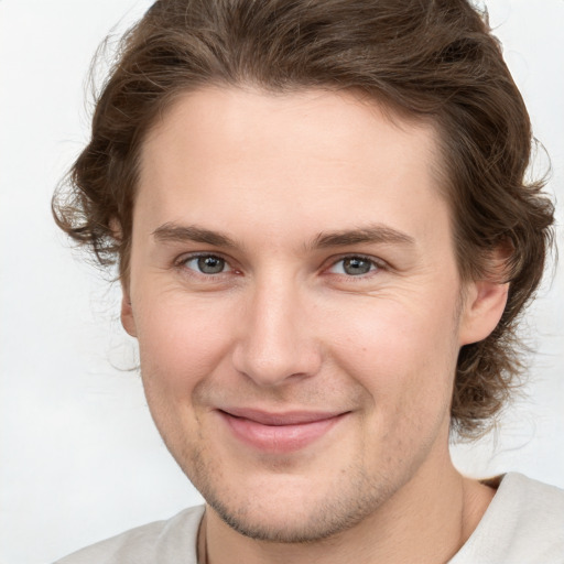 Joyful white young-adult male with medium  brown hair and grey eyes