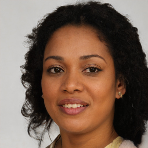 Joyful black young-adult female with long  brown hair and brown eyes