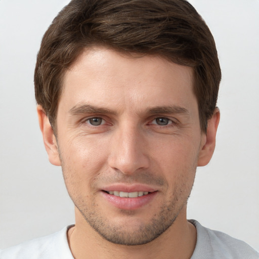 Joyful white young-adult male with short  brown hair and grey eyes