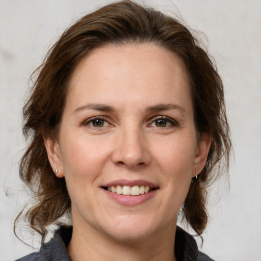 Joyful white adult female with medium  brown hair and grey eyes