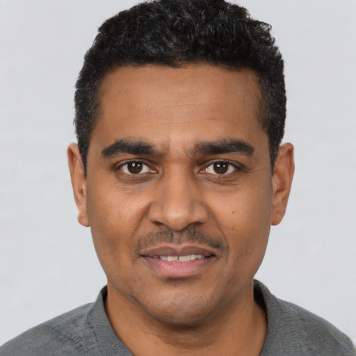 Joyful black young-adult male with short  black hair and brown eyes