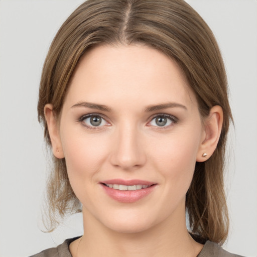 Joyful white young-adult female with medium  brown hair and grey eyes