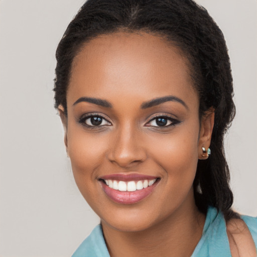 Joyful black young-adult female with long  black hair and brown eyes