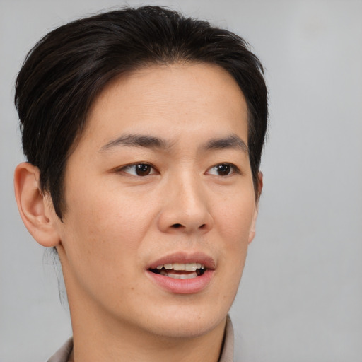 Joyful asian young-adult male with short  brown hair and brown eyes