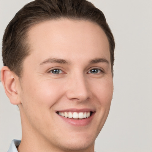 Joyful white young-adult male with short  brown hair and grey eyes