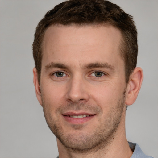 Joyful white young-adult male with short  brown hair and grey eyes