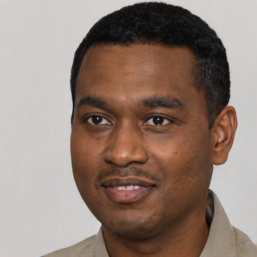 Joyful black young-adult male with short  black hair and brown eyes