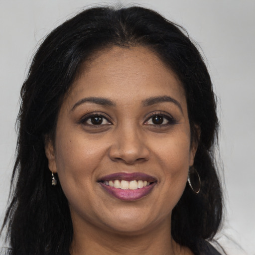 Joyful black young-adult female with long  brown hair and brown eyes