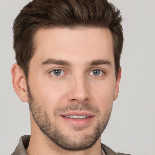 Joyful white young-adult male with short  brown hair and grey eyes