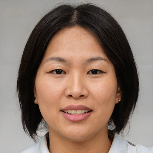 Joyful asian adult female with medium  brown hair and brown eyes