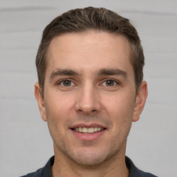 Joyful white young-adult male with short  brown hair and grey eyes