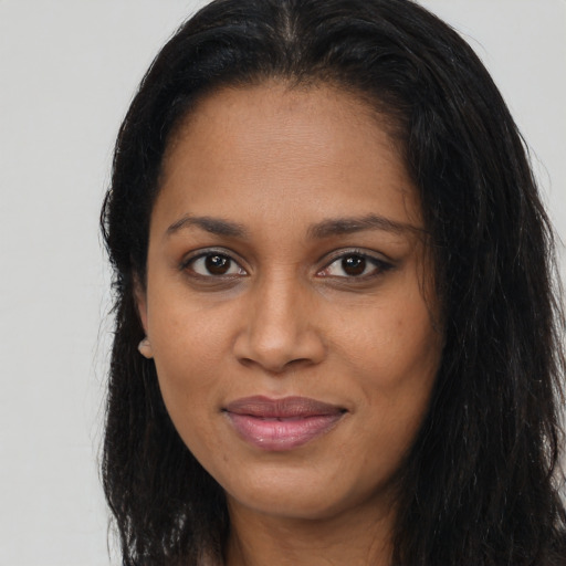 Joyful black young-adult female with long  brown hair and brown eyes