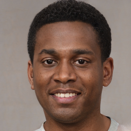 Joyful black young-adult male with short  black hair and brown eyes