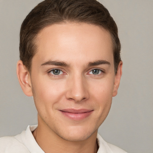 Joyful white young-adult male with short  brown hair and grey eyes