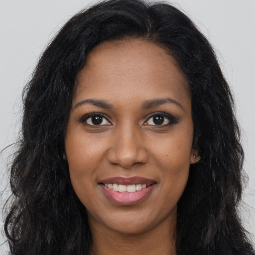 Joyful black young-adult female with long  brown hair and brown eyes
