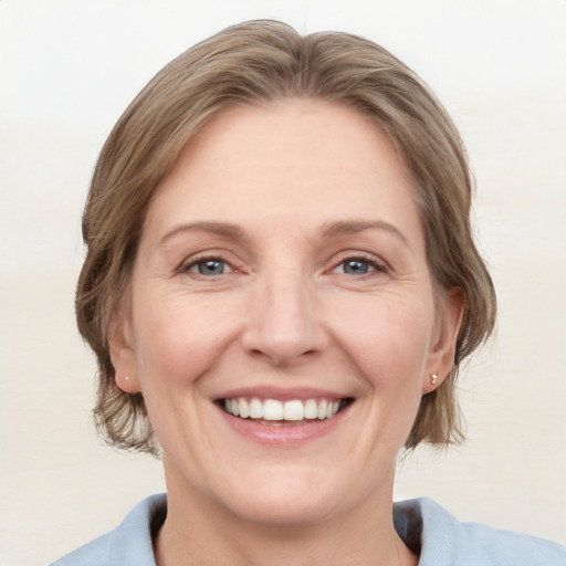 Joyful white adult female with medium  brown hair and blue eyes