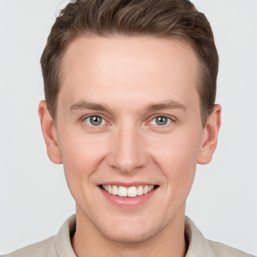 Joyful white young-adult male with short  brown hair and grey eyes