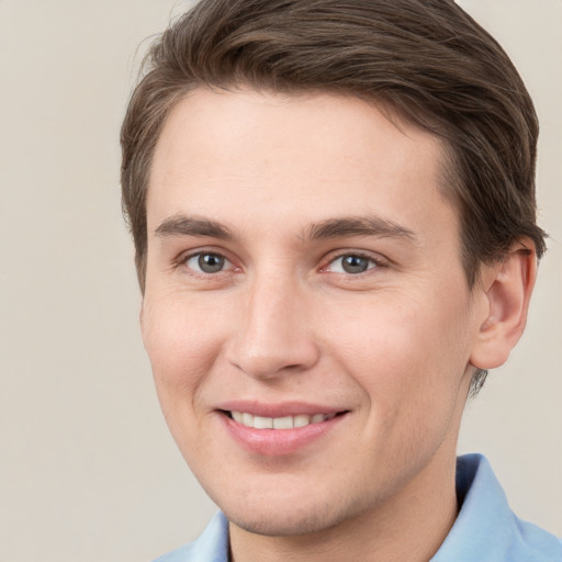 Joyful white young-adult male with short  brown hair and grey eyes