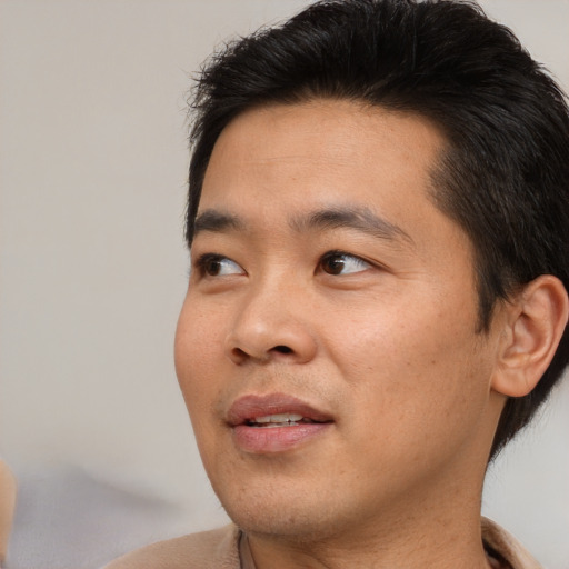 Joyful asian adult male with short  brown hair and brown eyes