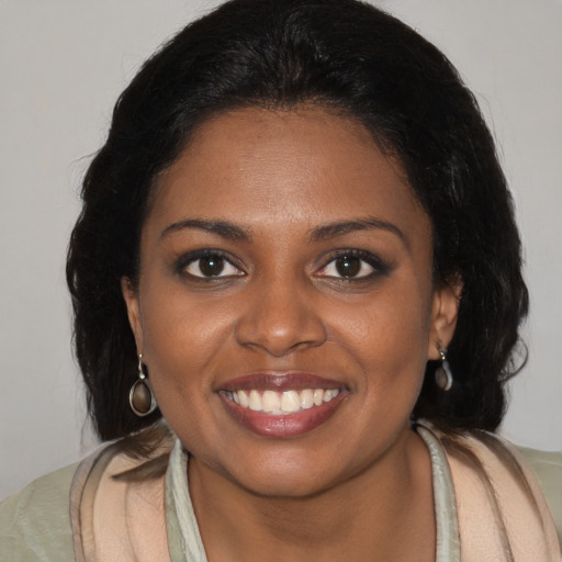 Joyful black young-adult female with long  brown hair and brown eyes