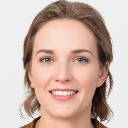 Joyful white young-adult female with medium  brown hair and grey eyes