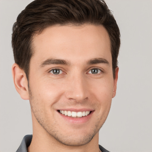 Joyful white young-adult male with short  brown hair and grey eyes