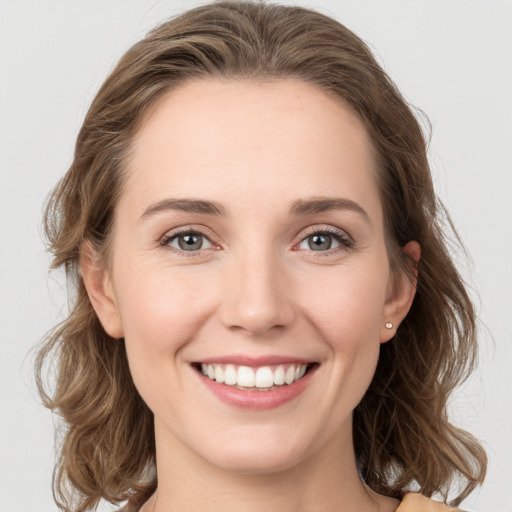 Joyful white young-adult female with medium  brown hair and grey eyes