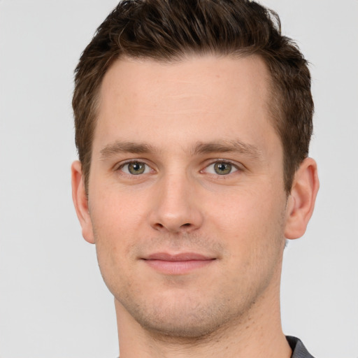 Joyful white young-adult male with short  brown hair and grey eyes