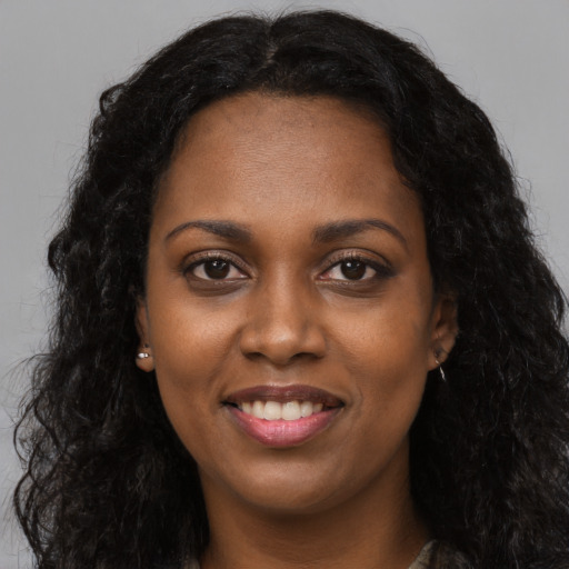 Joyful black young-adult female with long  black hair and brown eyes