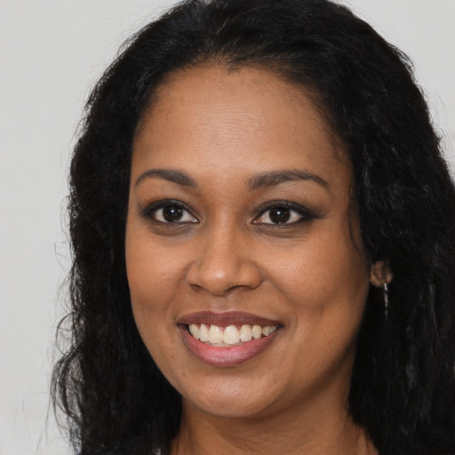 Joyful black young-adult female with long  brown hair and brown eyes