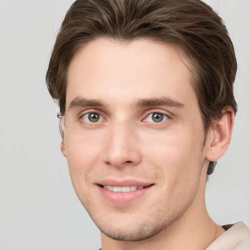 Joyful white young-adult male with short  brown hair and grey eyes