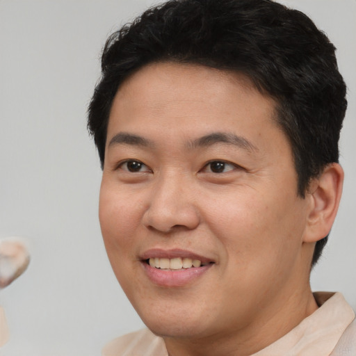 Joyful asian young-adult male with short  brown hair and brown eyes