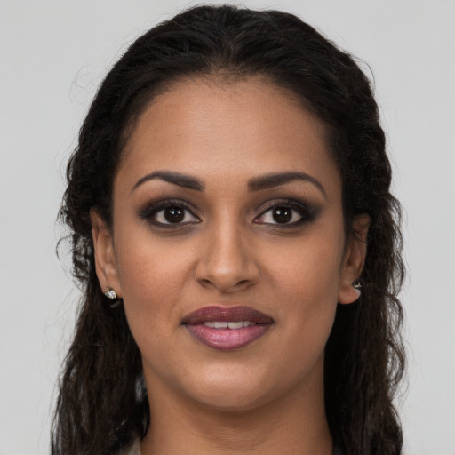 Joyful black young-adult female with long  brown hair and brown eyes