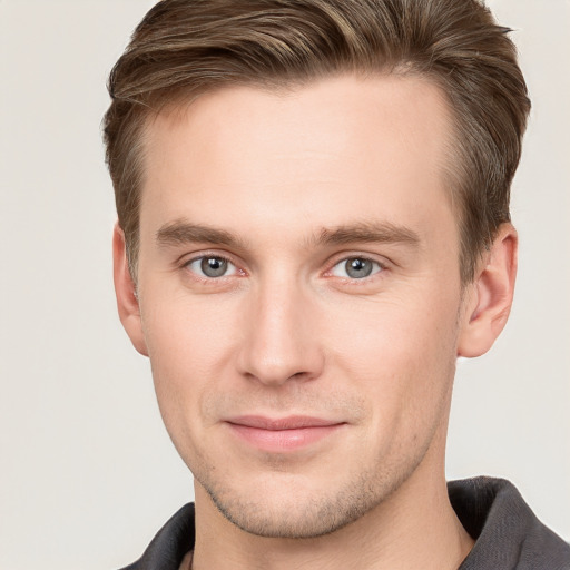 Joyful white young-adult male with short  brown hair and grey eyes