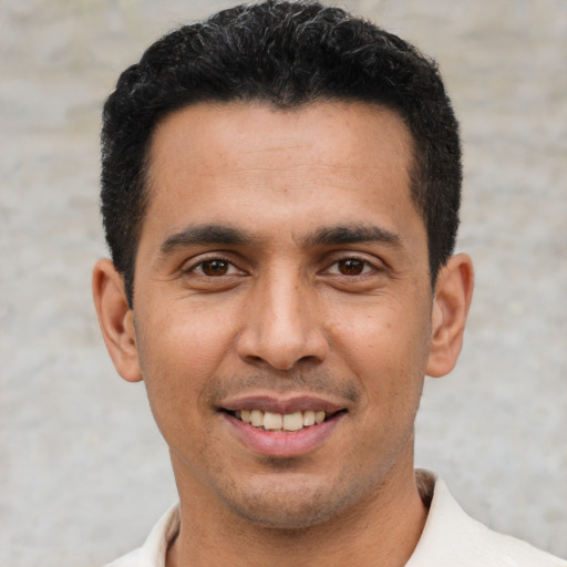 Joyful latino young-adult male with short  black hair and brown eyes