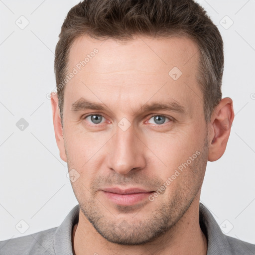 Joyful white young-adult male with short  brown hair and grey eyes