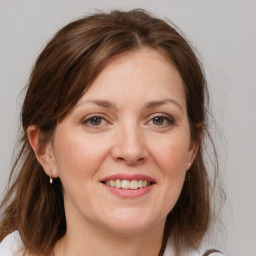 Joyful white young-adult female with medium  brown hair and grey eyes