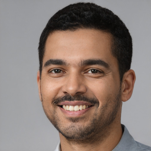Joyful latino young-adult male with short  black hair and brown eyes