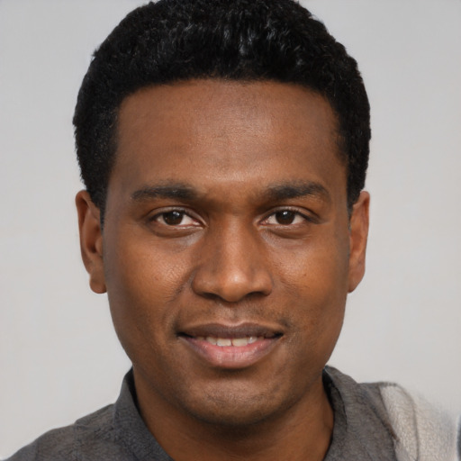 Joyful black young-adult male with short  black hair and brown eyes