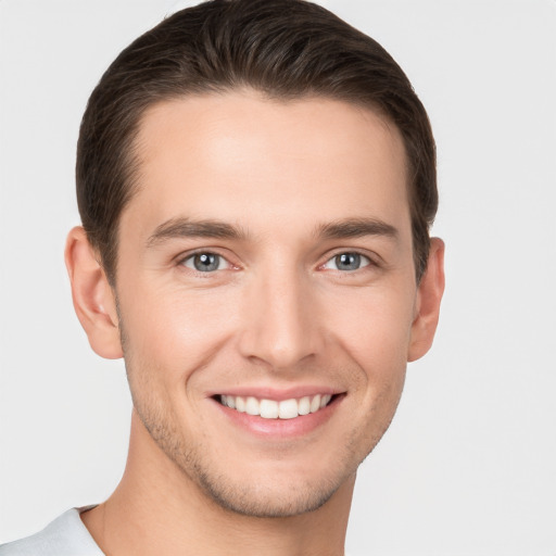 Joyful white young-adult male with short  brown hair and grey eyes