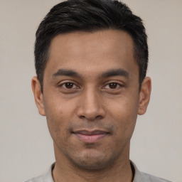 Joyful latino young-adult male with short  black hair and brown eyes