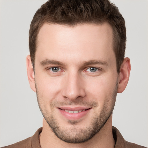 Joyful white young-adult male with short  brown hair and grey eyes