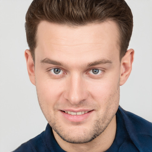 Joyful white young-adult male with short  brown hair and grey eyes