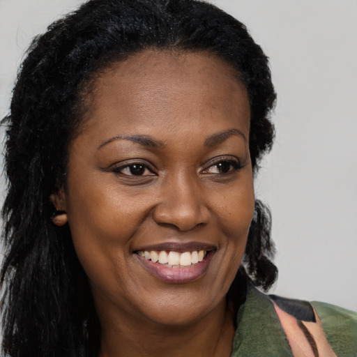 Joyful black young-adult female with long  brown hair and brown eyes