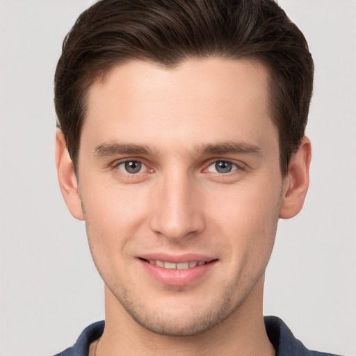 Joyful white young-adult male with short  brown hair and grey eyes